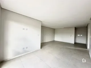 Foto do interior de um espaço com piso de cerâmica e paredes brancas.
