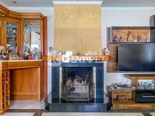 Sala de estar com lareira e televisão montada na parede.