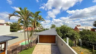 Vista externa de uma propriedade com vegetação exuberante e telhado de telhas.