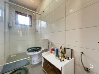 Foto interna de um banheiro com revestimento cerâmico e box de vidro.