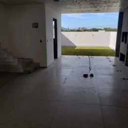 Vista de um espaço interno com piso de concreto e parede branca.