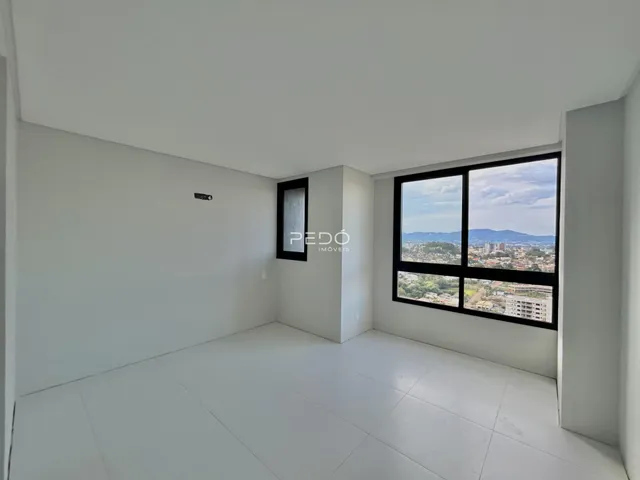 Ambiente interno de uma sala ampla com vista para a paisagem urbana.