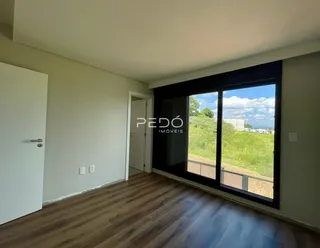 Vista interna de uma sala com piso de madeira e porta de vidro.