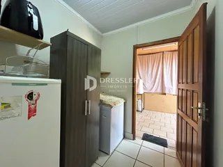 Hall de entrada com portas de madeira e vista para outro cômodo.