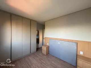 Quarto com armários embutidos e piso de madeira.