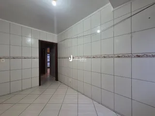 Corredor interno com piso de cerâmica e paredes brancas.