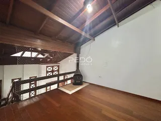 Imagem de uma sala de estar com piso de madeira e teto de madeira aparente.