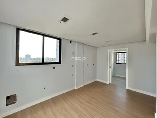 Sala de estar com piso de madeira e grande janela de vista para a cidade.