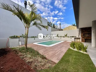 Piscina externa com deck de madeira e paisagismo em um imóvel.