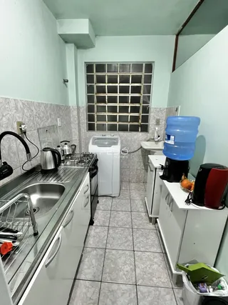 Foto da cozinha mostrando bancada de aço inoxidável e máquina de lavar roupa.