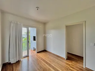 Ambiente interno de uma sala com piso de madeira e porta de vidro.