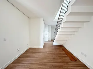 Hall de entrada com piso de madeira e escadaria.