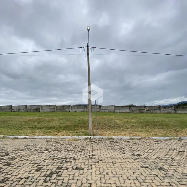 Vista externa de um terreno com muro e gramado.