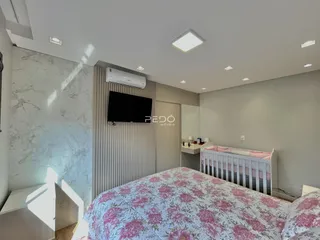 Quarto moderno com cama e televisão montada na parede.