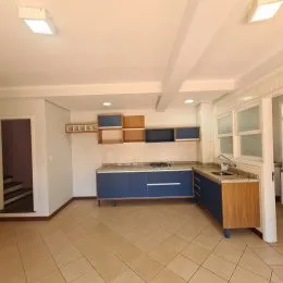 Foto interna de uma cozinha com armários em madeira clara.