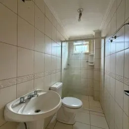Corredor interno com paredes brancas e azulejos.