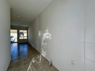 Corredor interno de uma residência com piso de cerâmica escura.