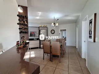 Foto de uma cozinha com armários brancos e mesa de jantar de madeira.