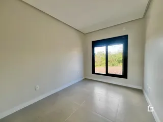 Uma sala de estar com paredes brancas e piso claro.