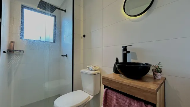Banheiro com box de vidro e bancada de madeira.
