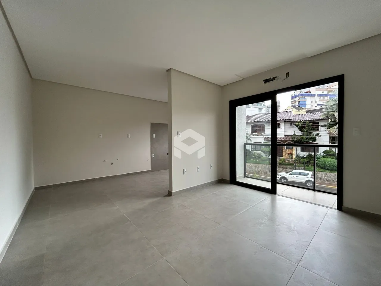 Espaço interno de uma residência com paredes brancas e piso de concreto.