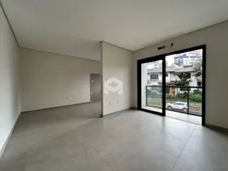 Espaço interno de uma residência com paredes brancas e piso de concreto.