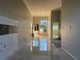 Hall de entrada com piso polido e paredes brancas em um imóvel em Lajeado.