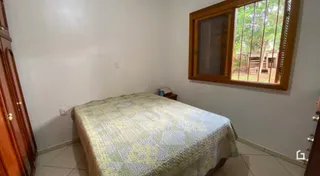Quarto com cama de casal e janela de madeira.
