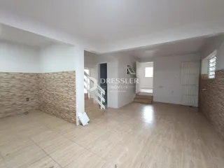 Vista de um corredor interno com paredes de tijolo aparente e piso de cerâmica.