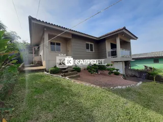 Fachada de uma casa em Lajeado, Brasil, com gramado verde e paisagismo.