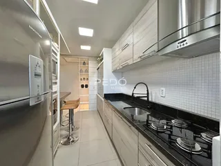 Cozinha moderna com armários e bancadas escuras em um imóvel no Brasil.