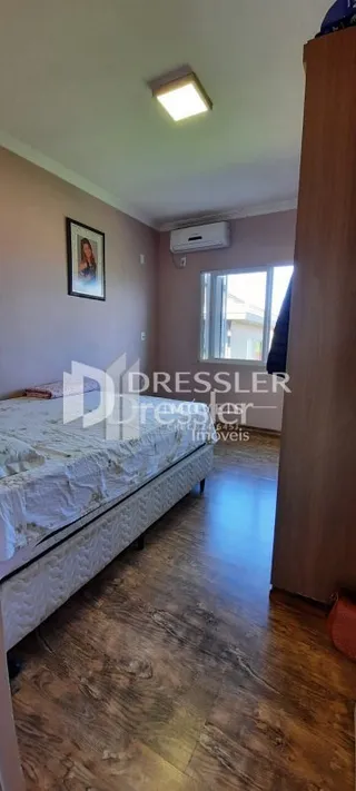 Quarto com cama e piso de madeira no interior da propriedade.