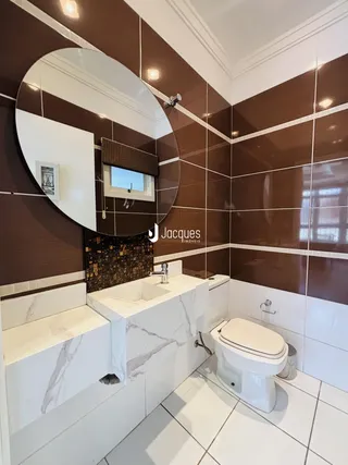 Foto de um banheiro com revestimento de azulejos marrons e brancos.