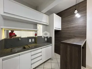 Vista da cozinha moderna com armários brancos e detalhes em madeira escura.