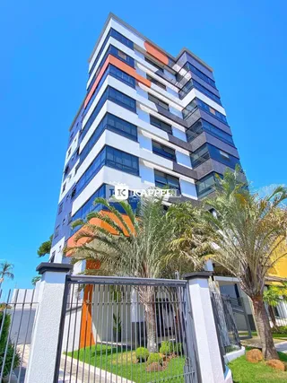 Fachada de um prédio residencial moderno com vegetação e palmeiras.