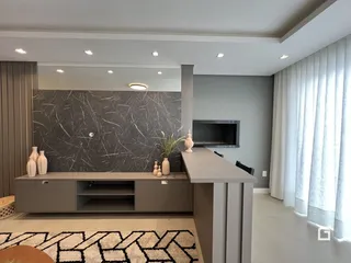 Sala de estar moderna com parede de mármore escuro e móveis planejados.