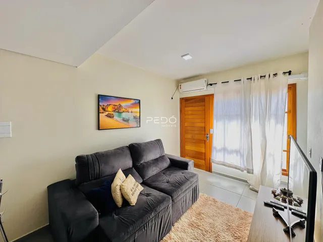 Sala de estar com sofá cinza e televisão na parede.