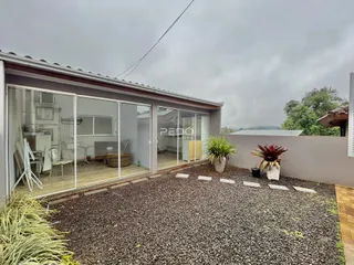 Fachada de uma residência moderna com grandes portas de vidro e pátio.
