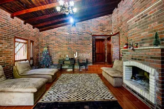 Sala de estar com paredes de tijolo aparente e lareira em um imóvel no Brasil.