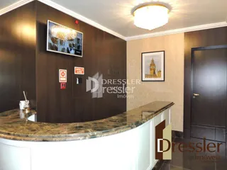 Vista de uma cozinha com armários escuros e bancada de granito.