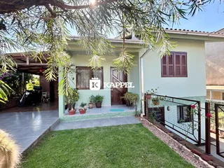Fachada de uma casa verde em Lajeado, Brasil, com jardim e varanda.