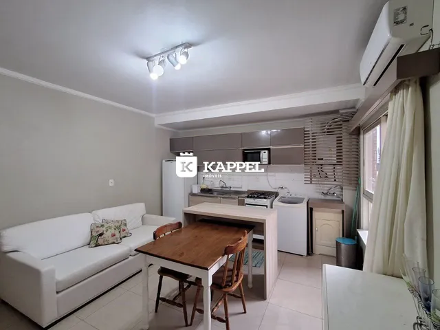 Sala de estar com sofá branco e mesa de madeira em um apartamento.
