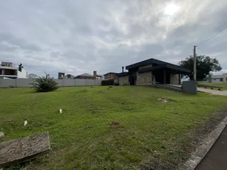 Fachada de uma casa moderna com telhado escuro e um grande gramado em primeiro plano.