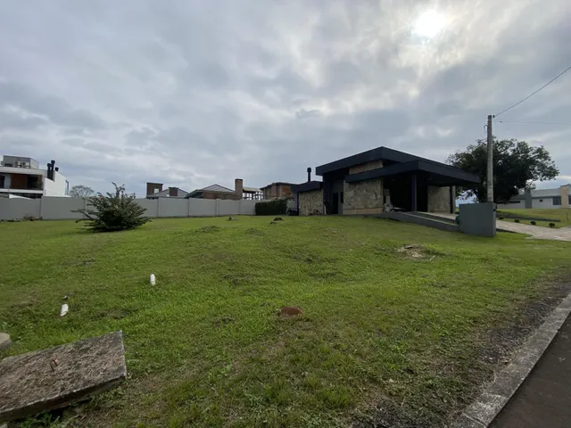 Fachada de uma casa moderna com telhado escuro e um grande gramado em primeiro plano.