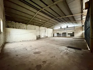 Imagem interna de um grande espaço industrial com paredes de tijolo aparente.