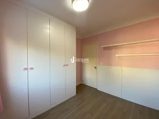Interior de um cômodo com armários brancos e paredes rosa.
