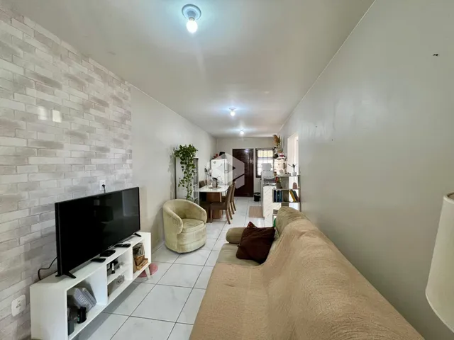 Interior de uma sala de estar com piso de cerâmica e parede de tijolos brancos.