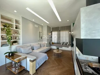 Sala de estar ampla com piso de madeira e estantes de parede.