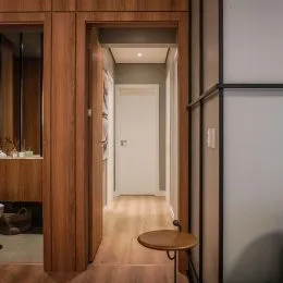Hall de entrada com revestimento de madeira e porta branca.