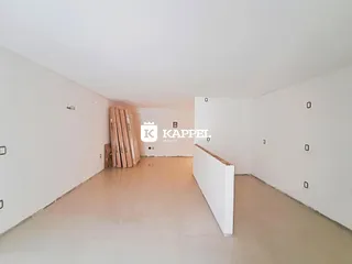 Hall de entrada com paredes brancas e materiais de construção visíveis.